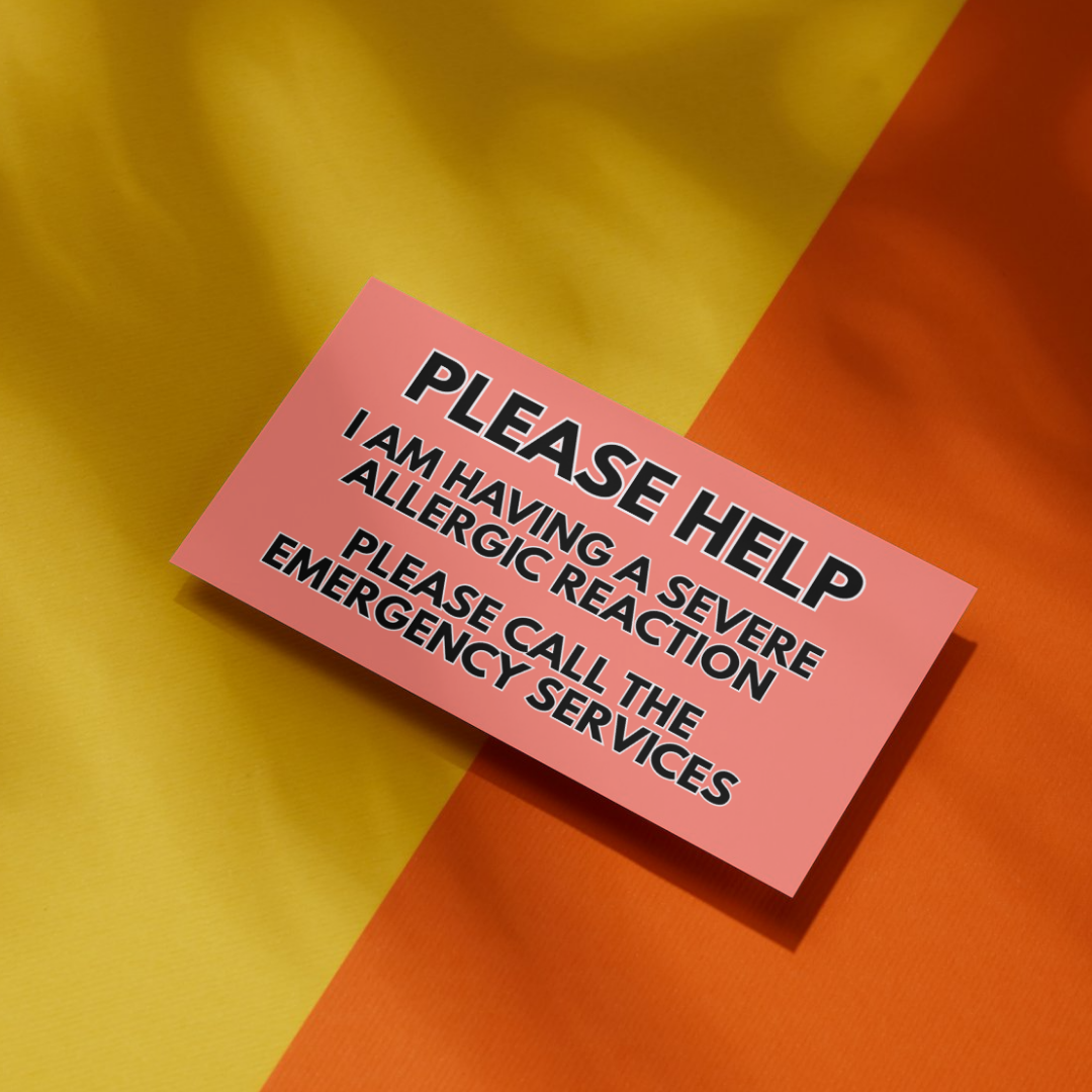 medical alert card reading "PLEASE HELP I am having a severe allergic reaction. Please call the emergency services" On a yellow and orange background.