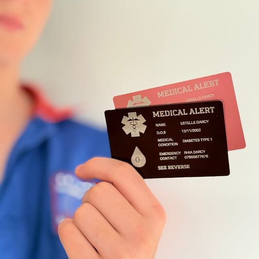 Person holding two medical alert cards, one black and one red.