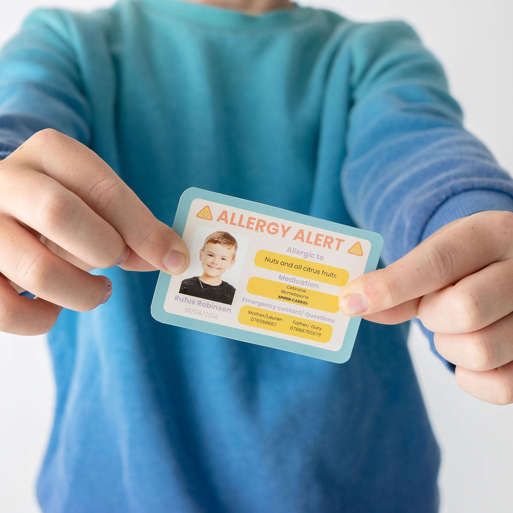 Person holding an allergy alert card with a child's photo and details.