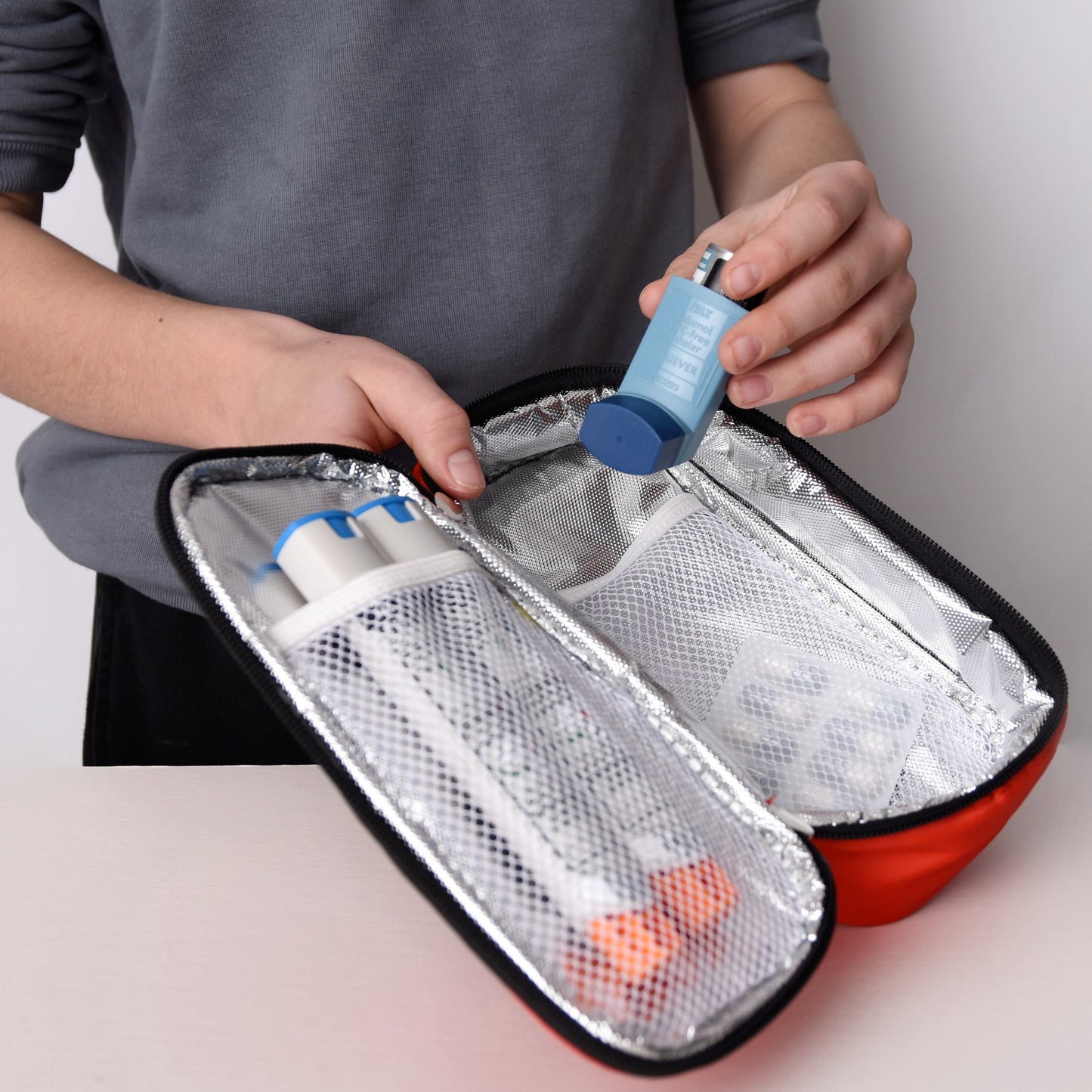Person holding a small insulated bag with medical supplies on a plain background